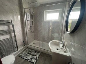 A modern bathroom with a glass-enclosed shower, a white sink, and a towel rack. - Salakee (Penzance)