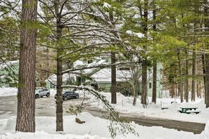 A snow-covered residential area with a green house, parked cars, and a picnic table. - 1 Mi to Attitash Mountain: Condo w/ Resort Perks (Bartlett)