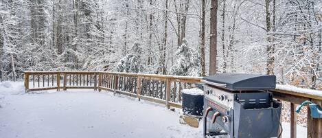 Ein mit Schnee bedeckter Deck mit Grill und Mülleimer.