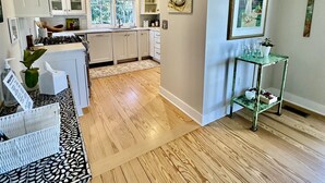 A modern kitchen with white cabinets, a wooden countertop, and a window with patterned curtains.