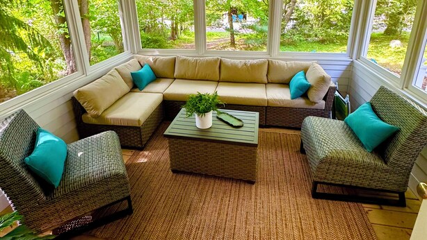 A sunroom with a sectional sofa, two armchairs, a coffee table, and a ceiling fan.
