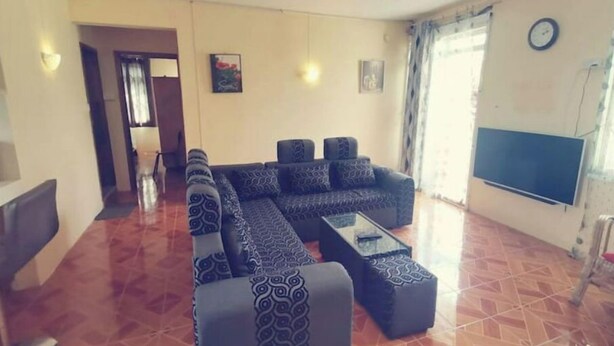 Ein Wohnzimmer mit Ecksofa, Couchtisch und Flachbildfernseher.
