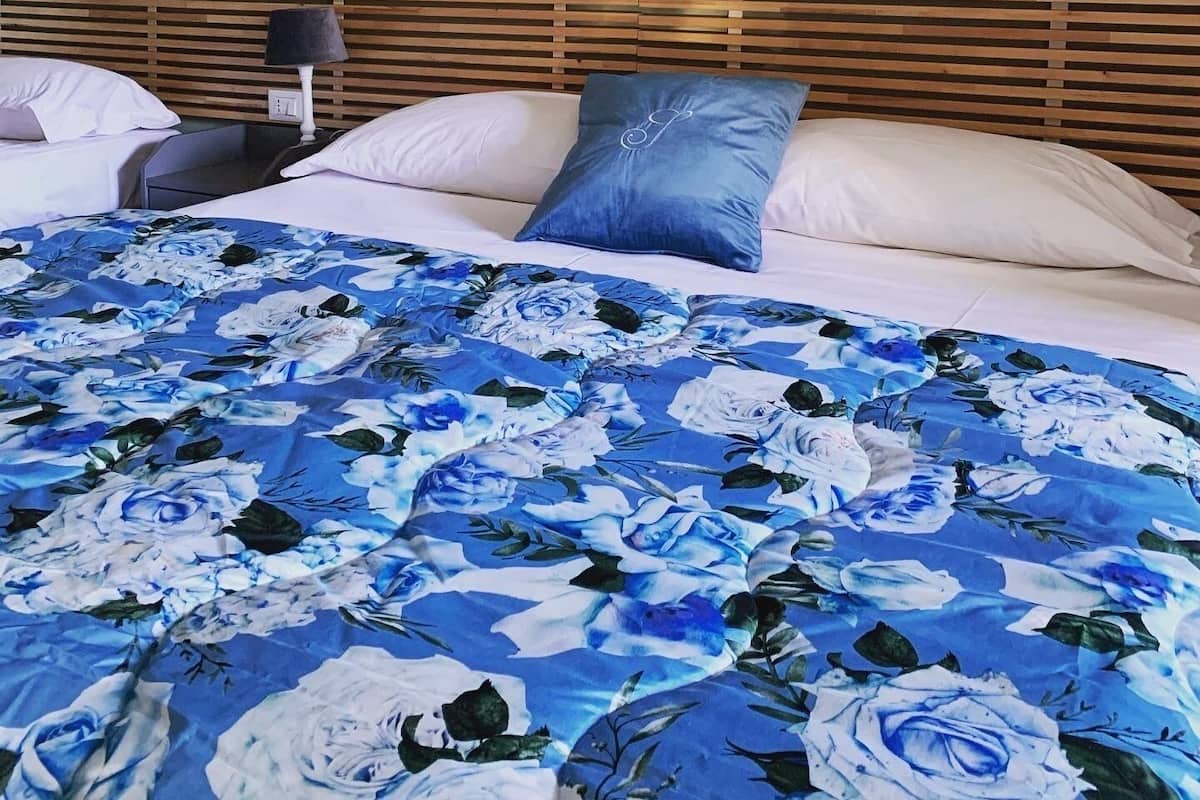 A hotel room with a bed, a nightstand, a lamp, and a wooden headboard.