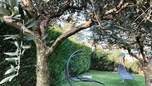 Un jardín con un árbol, un seto y una escultura de metal.