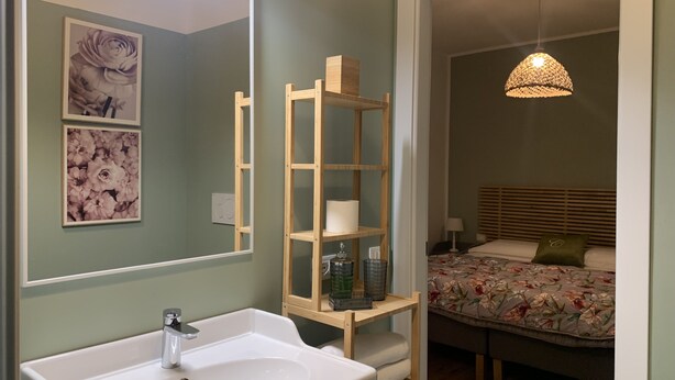 Un baño con un lavabo blanco, un espejo y una repisa de madera con artículos de tocador.