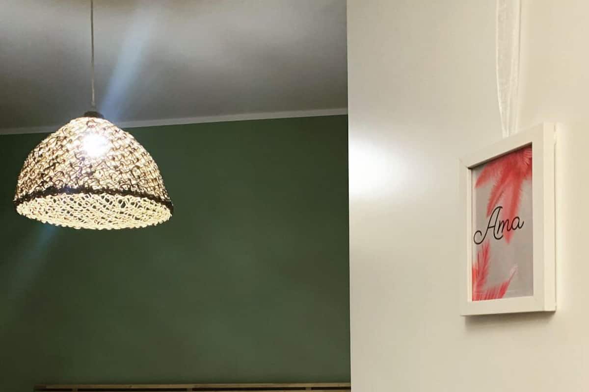 A bedroom with a bed, a hanging light fixture, a framed artwork on the wall, and a door.