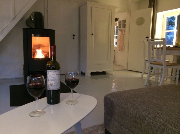 A cozy living room with a fireplace, a table with two wine glasses and a bottle, and a sofa. - Charming artist's studio (Worpswede)