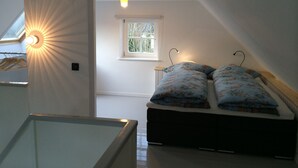 A bedroom with a skylight, a window, and a bed with floral bedding. - Charming artist's studio (Worpswede)