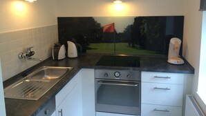 A modern kitchen with a stainless steel sink, a built-in oven, and a large window with a view of a golf course. - Charming artist's studio (Worpswede)