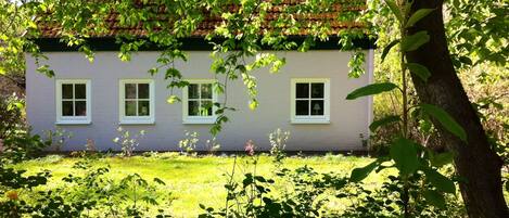 A house with a white exterior, a red-tiled roof, and three windows.