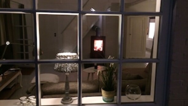 A room with a large window divided into multiple panes, a sofa, a small table, a lamp, a potted plant, and a decorative glass sphere. - Charming artist's studio (Worpswede)