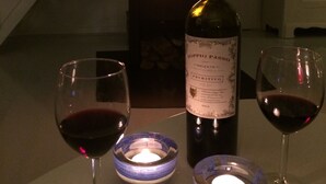 A bottle of wine, two glasses of red wine, and a lit candle on a table. - Charming artist's studio (Worpswede)