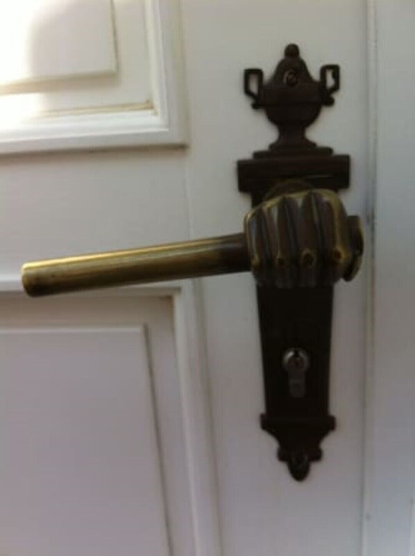 A brass door handle with a keyhole and a decorative finial on a white door.