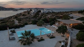 A resort with a swimming pool, outdoor seating, and a view of the sea and hills. - Naousa Bay Views with pool - Villa Caroline (Naousa)