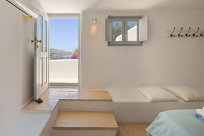 A bedroom with a bed, a small window, a door, and a view of the outdoors. - Naousa Bay Views with pool - Villa Caroline (Naousa)