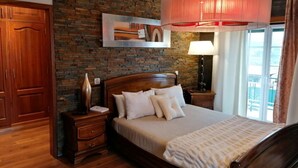 Una camera da letto con parete in mattoni, struttura letto in legno e una grande finestra con tende.