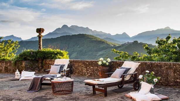 A terrace with two lounge chairs, a small round table, and a decorative column. The terrace overlooks a mountainous landscape. - Villa Raffaelli, original Tuscany villa from 1582 (Fosciandora)