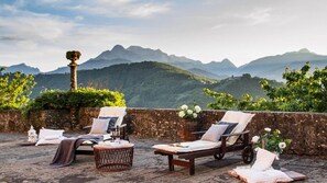 A terrace with two lounge chairs, a small round table, and a decorative column. The terrace overlooks a mountainous landscape. - Villa Raffaelli, original Tuscany villa from 1582 (Fosciandora)