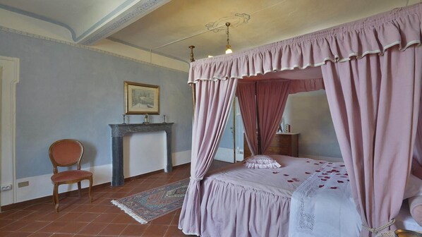 A bedroom with a four-poster bed, a chair, a fireplace, and a framed picture on the wall. - Villa Raffaelli, original Tuscany villa from 1582 (Fosciandora)