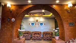 A lobby with a brick archway, three patterned sofas, and potted plants. - Hotel BnB Mhepi (Kathmandu)