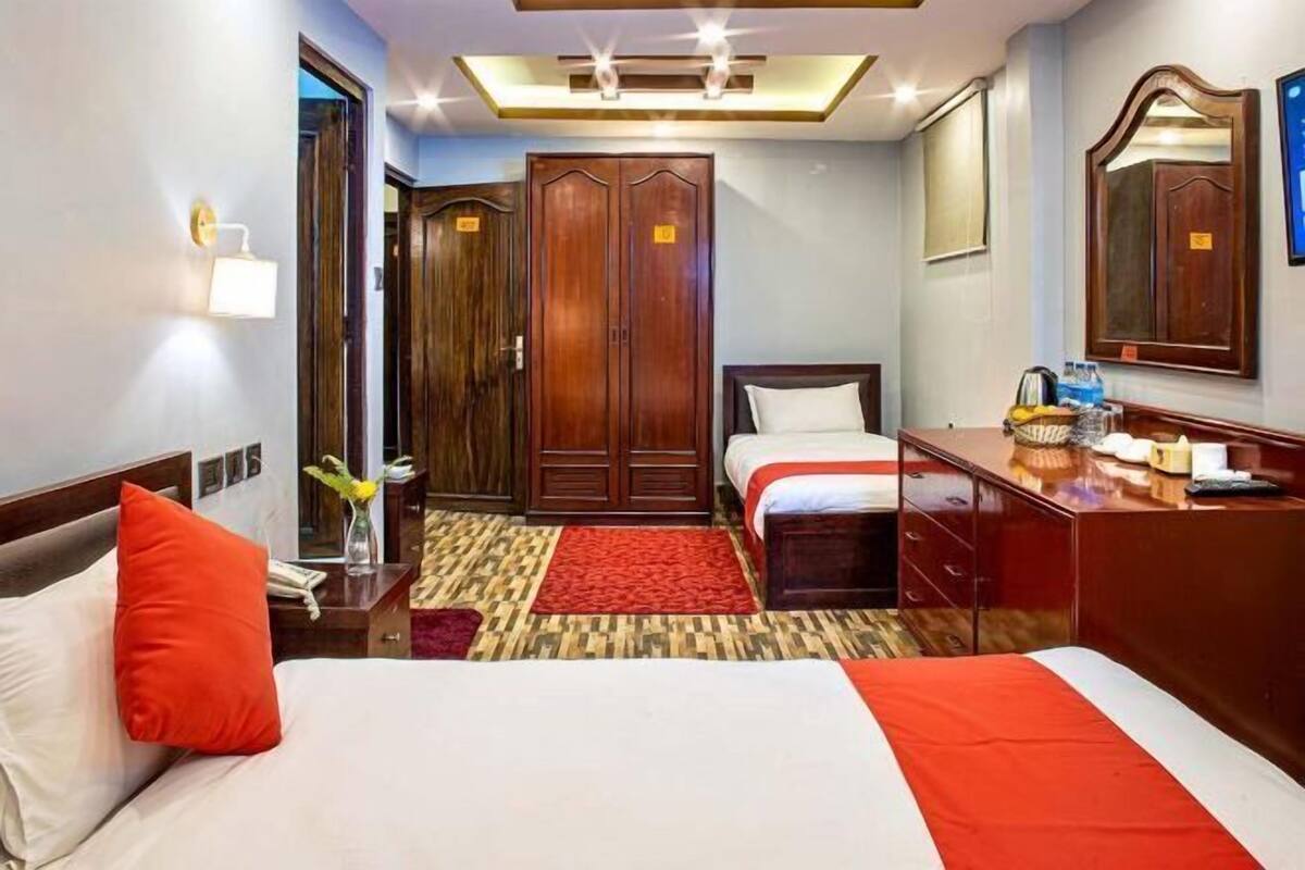 Ein Hotelzimmer mit Bett, Nachttisch, Lampe, Kleiderschrank und Spiegel.