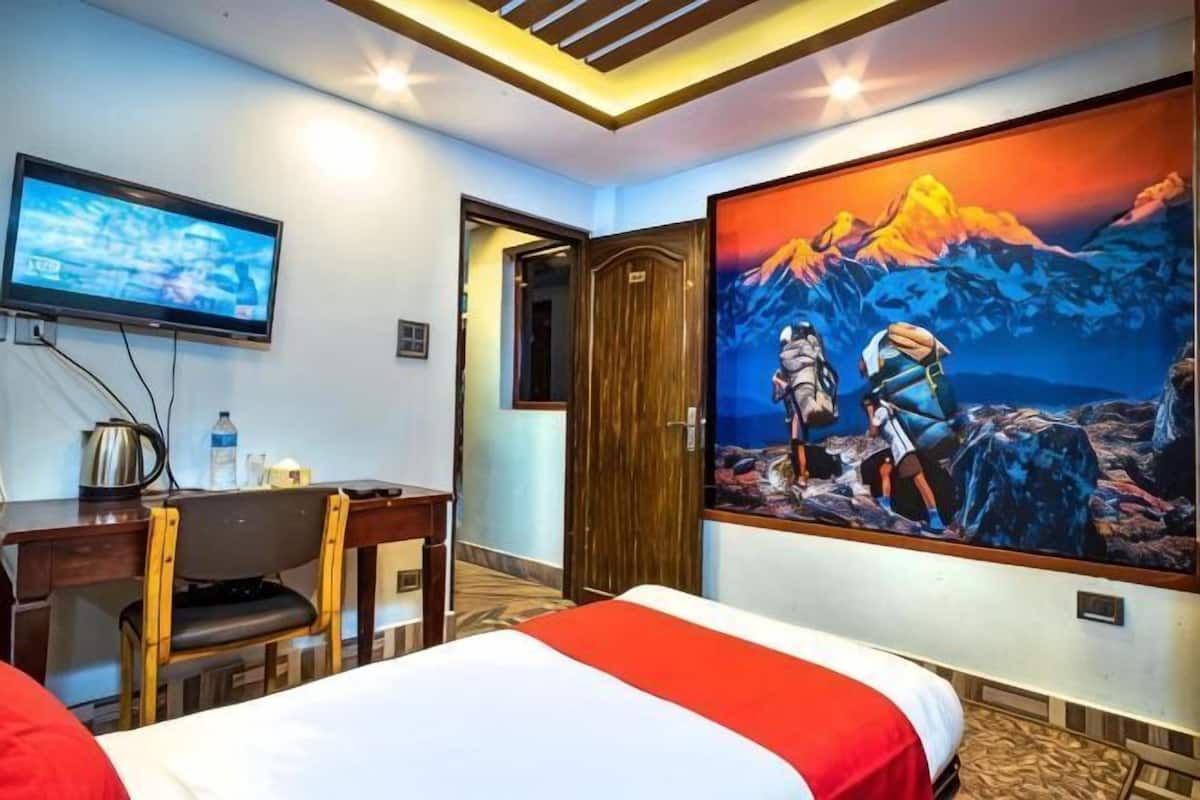 Ein Hotelzimmer mit Bett, Schreibtisch, Sessel, Fernseher und einem Bergpanorama.