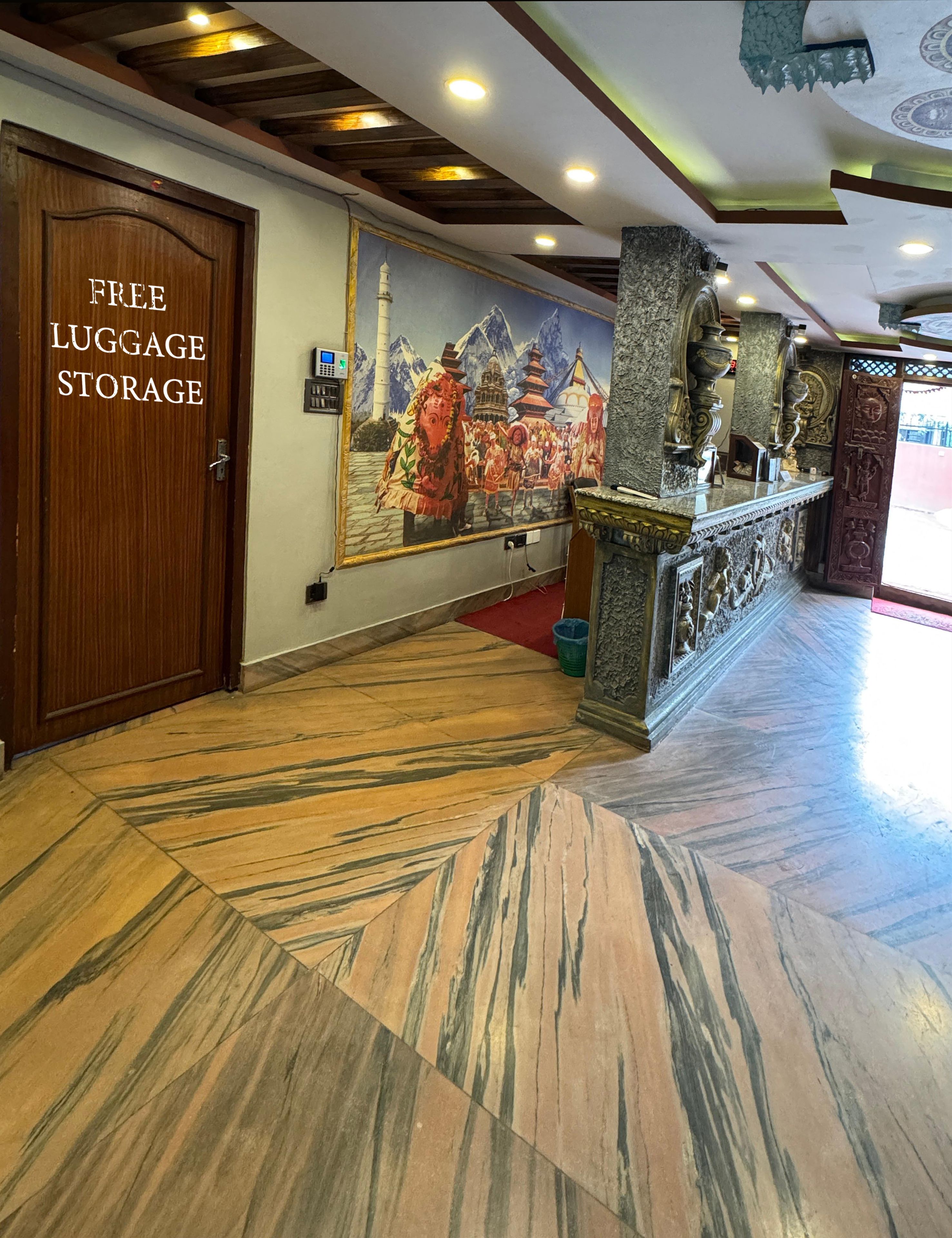 A lobby with a 'Free Luggage Storage' sign, a mural of a traditional scene, and a reception desk with a stone pillar.