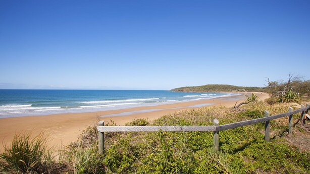 A beach with a wooden fence, sandy shore, and ocean waves. - Beach & Boats Agnes Water (AGNES WATER)