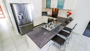 A modern kitchen with a stainless steel refrigerator, a built-in microwave, and a sink with a stainless steel basin. - Beach & Boats Agnes Water (AGNES WATER)
