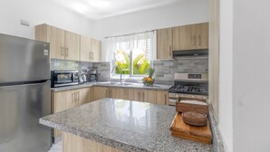 Une cuisine moderne dotée de plans de travail en granit, d’appareils électroménagers en acier inoxydable et d’armoires en bois.