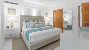 Une chambre à coucher avec un grand lit, deux tables de chevet avec des lampes, une porte en bois et un miroir.