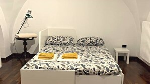 Un dormitorio con cama, una mesita de noche pequeña, una lámpara y un radiador.