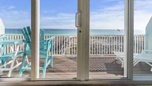 A view from a room with a sliding glass door to a deck with outdoor seating and a beach view. - Serenity Sands-Gulf Front 4 Bed Home Sleeps 10. Pup Friendly! (Navarre)