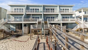 A beachfront hotel with multiple balconies, wooden walkways, and a sandy beach area. - Serenity Sands-Gulf Front 4 Bed Home Sleeps 10. Pup Friendly! (Navarre)