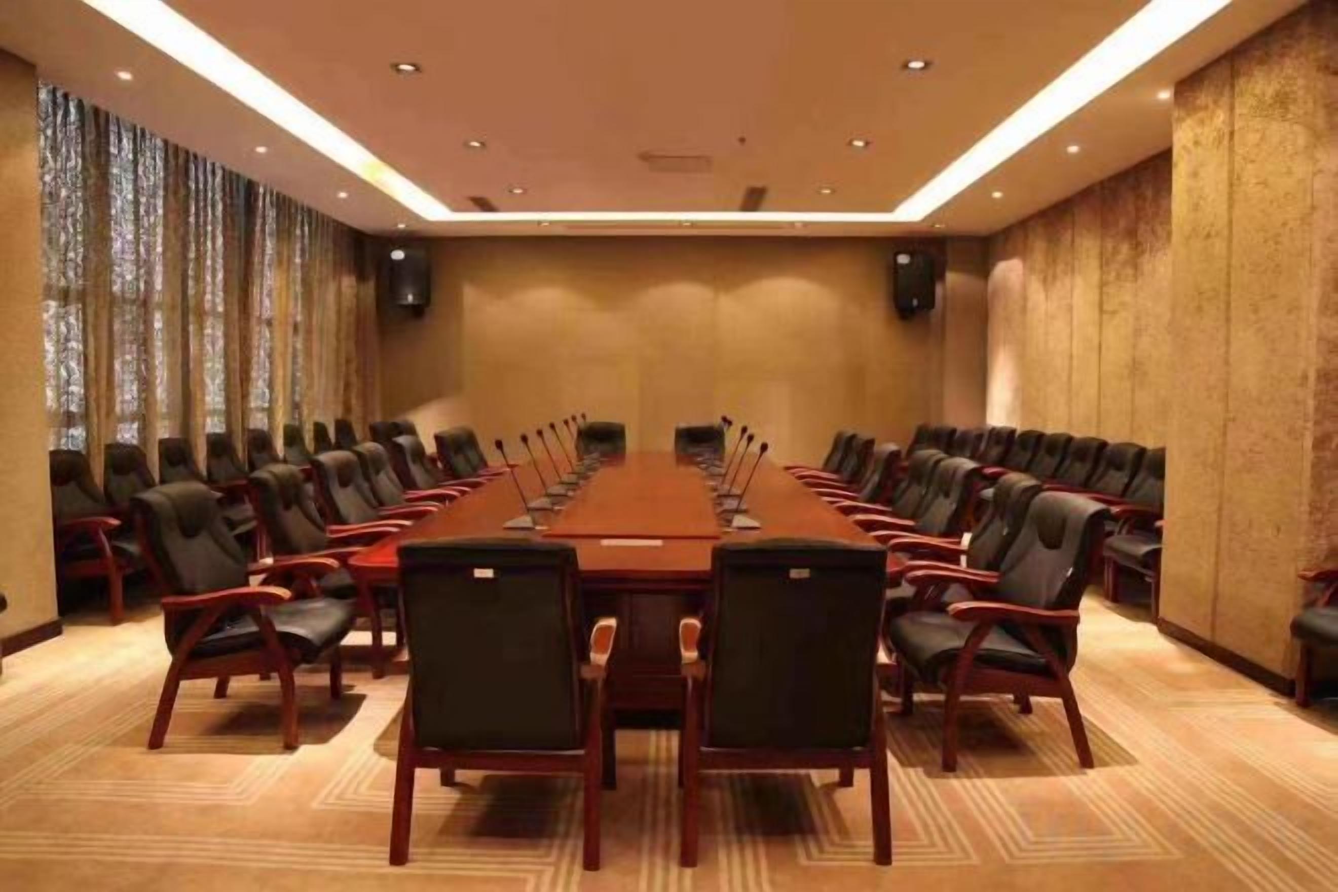 A conference room with a long table and chairs, large windows, and a carpeted floor.