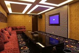 A conference room with a long table, red upholstered seating, and a flat-screen TV on the wall.