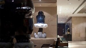 Un interior moderno con una escultura central, zona de estar y un techo alto con iluminación empotrada.