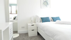 Une chambre à coucher comprenant un lit, une table de chevet, un miroir et un tableau accroché au mur.