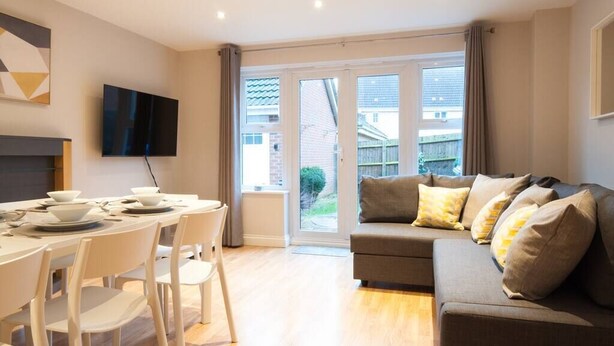 Un salon moderne avec un canapé, une table à manger et des chaises, et un téléviseur fixé au mur.