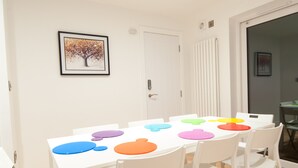 A dining area with a white table and chairs, a framed picture on the wall, and a door with a handle. - The Spitfire - Newly renovated 3-bed house in Cheltenham (Cheltenham)