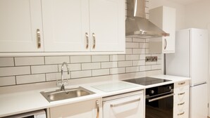 A modern kitchen with white cabinets, stainless steel appliances, and a tiled backsplash. - The Spitfire - Newly renovated 3-bed house in Cheltenham (Cheltenham)