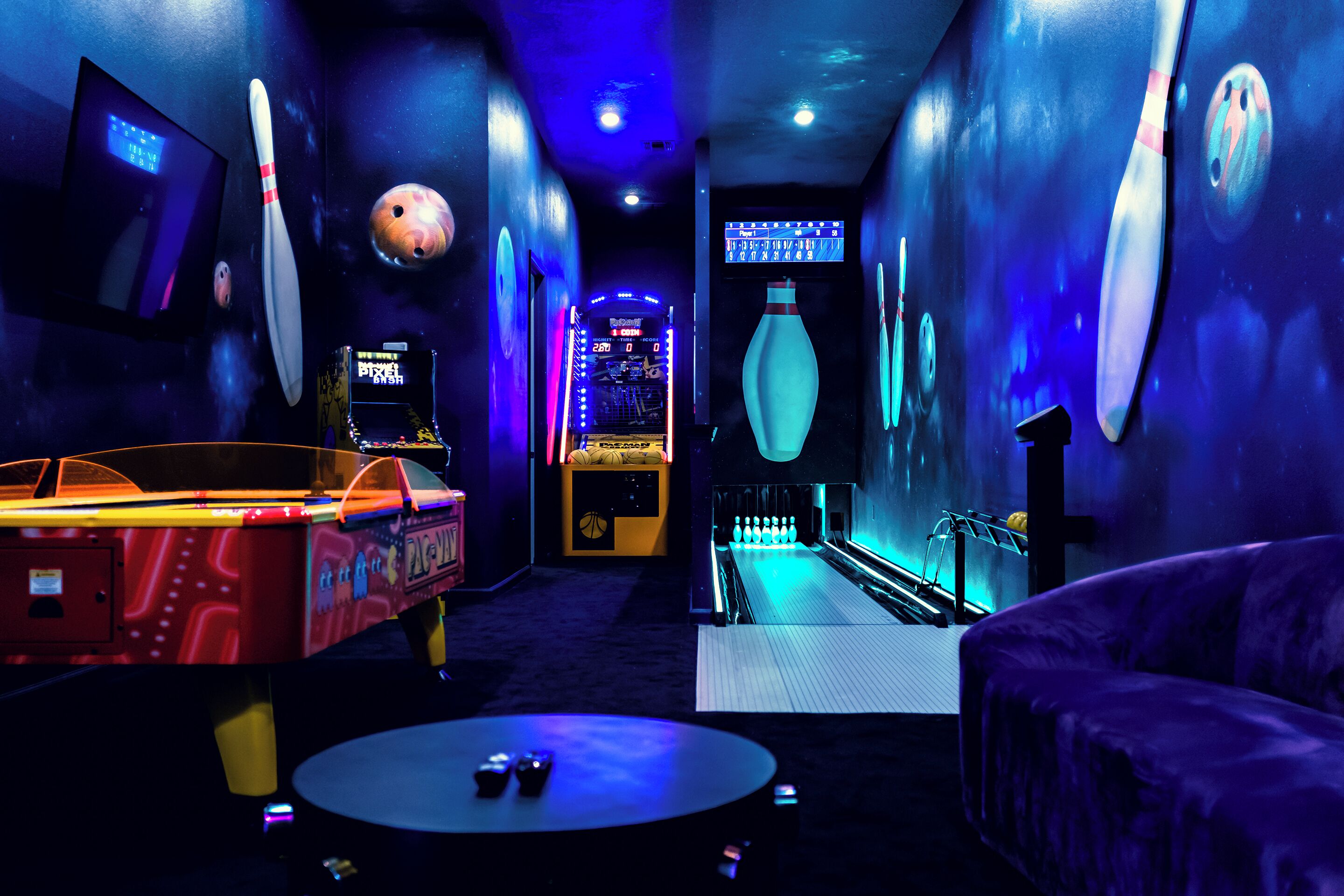 En bowlinghal med neonbelysning, en bowlingkugle og en kegleopsamler.
