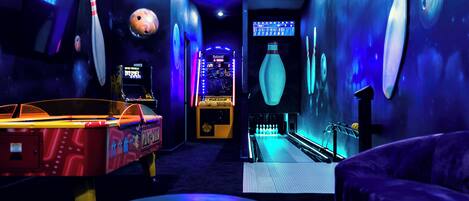 En bowlinghal med neonbelysning, en bowlingkugle og en kegleopsamler.