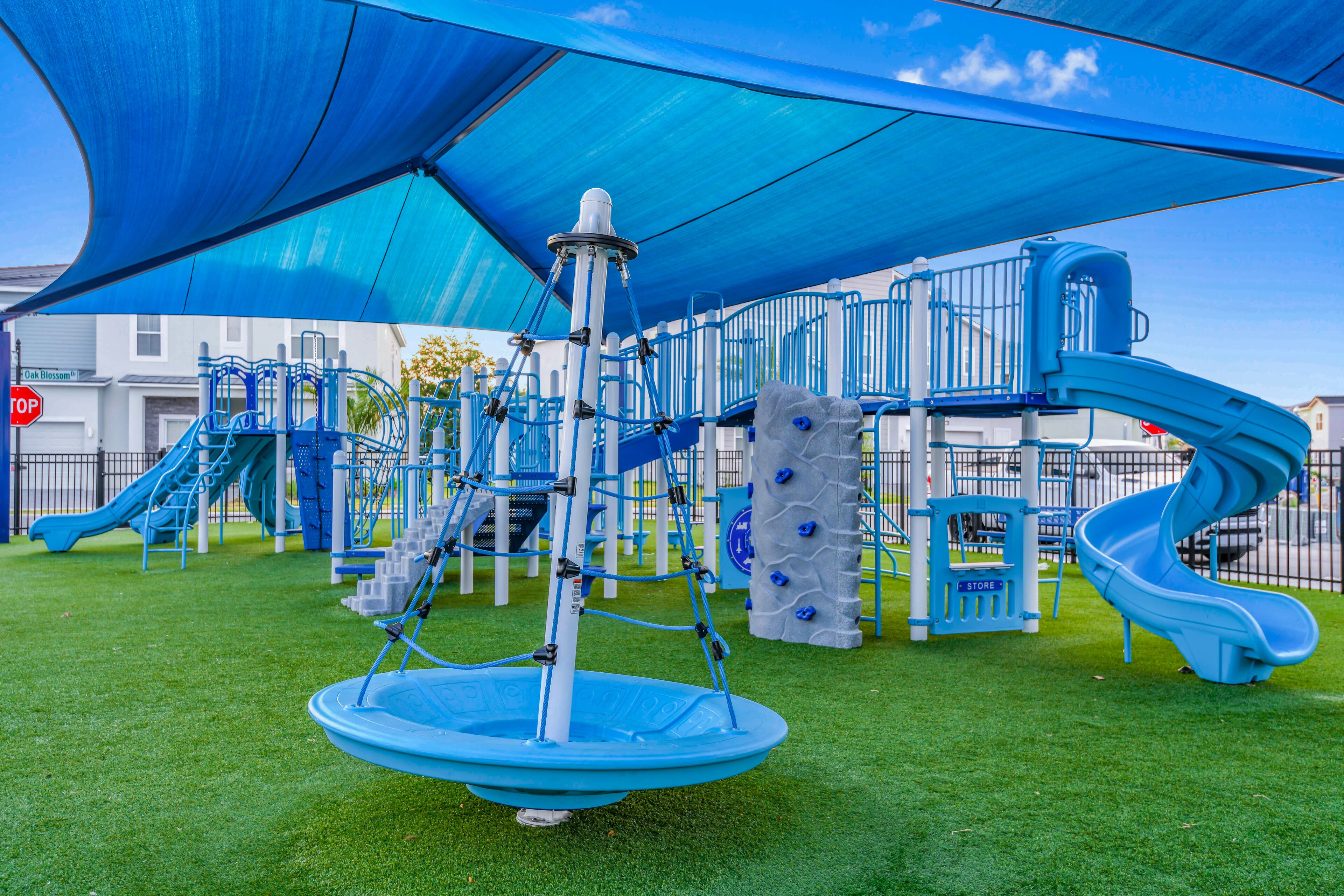 Une aire de jeux avec un toboggan bleu, des structures d’escalade et une balançoire.