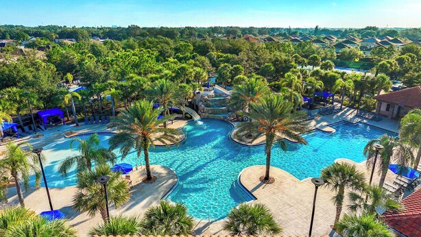 A resort with a large swimming pool surrounded by palm trees and lounge chairs. - The Village, Homes by Villatel (Davenport)