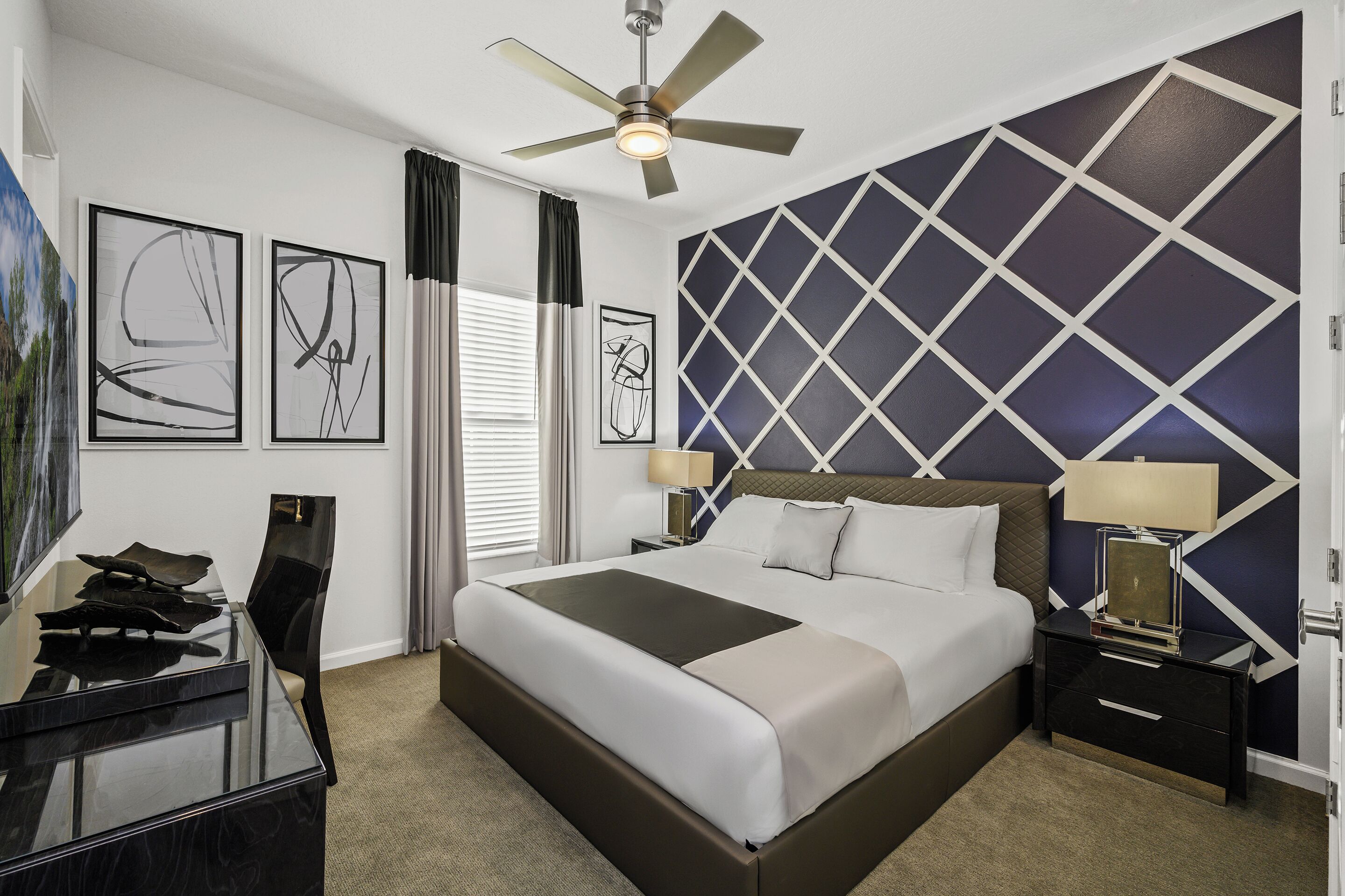 Une chambre d’hôtel moderne, dotée d’un grand lit, d’un bureau et d’un ventilateur de plafond.
