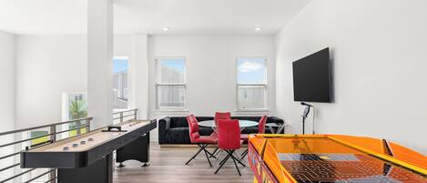 A modern indoor recreational area with a foosball table, pool table, and seating area.