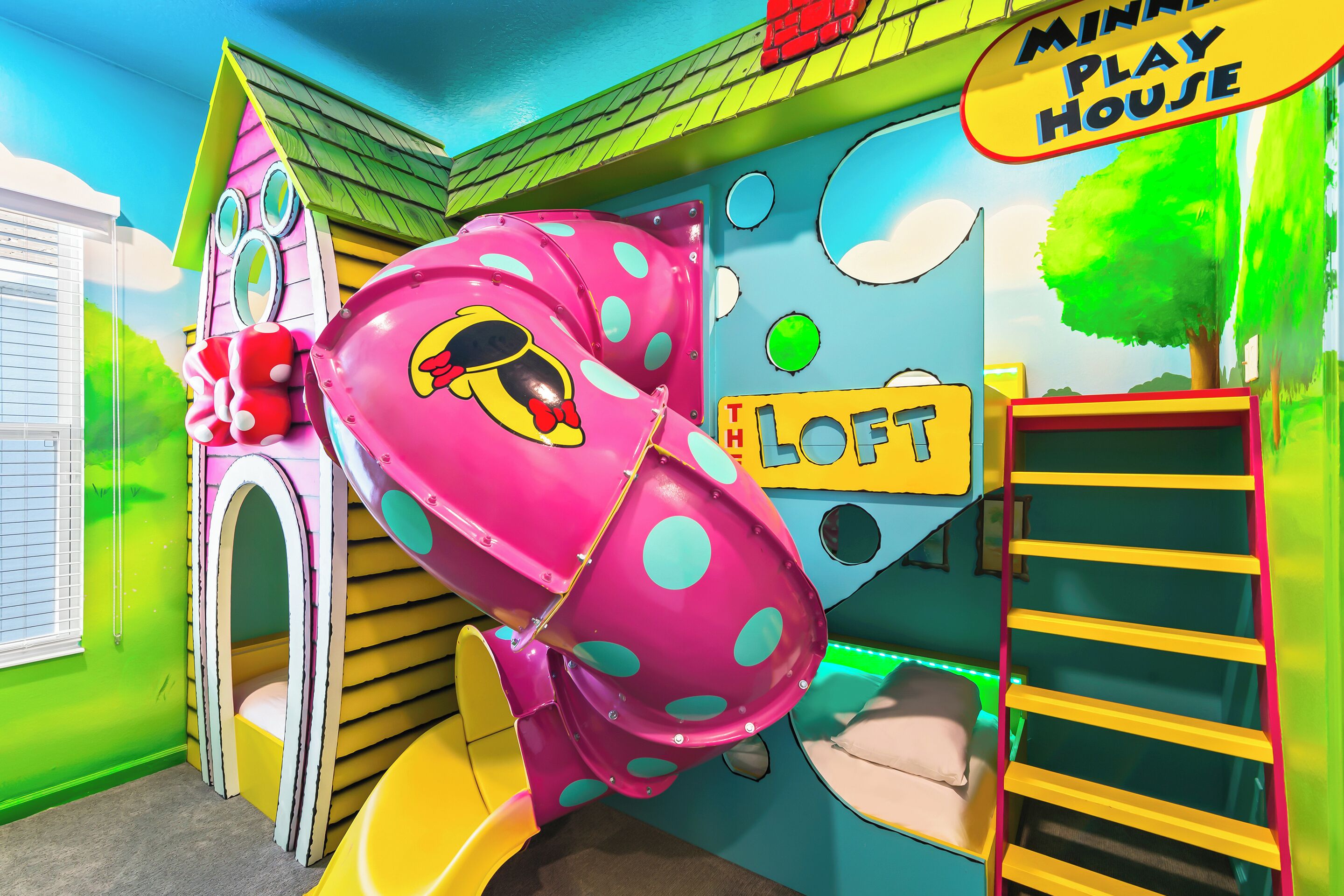 Un área de juegos infantiles con un tobogán, una pared de escalar y una casita.