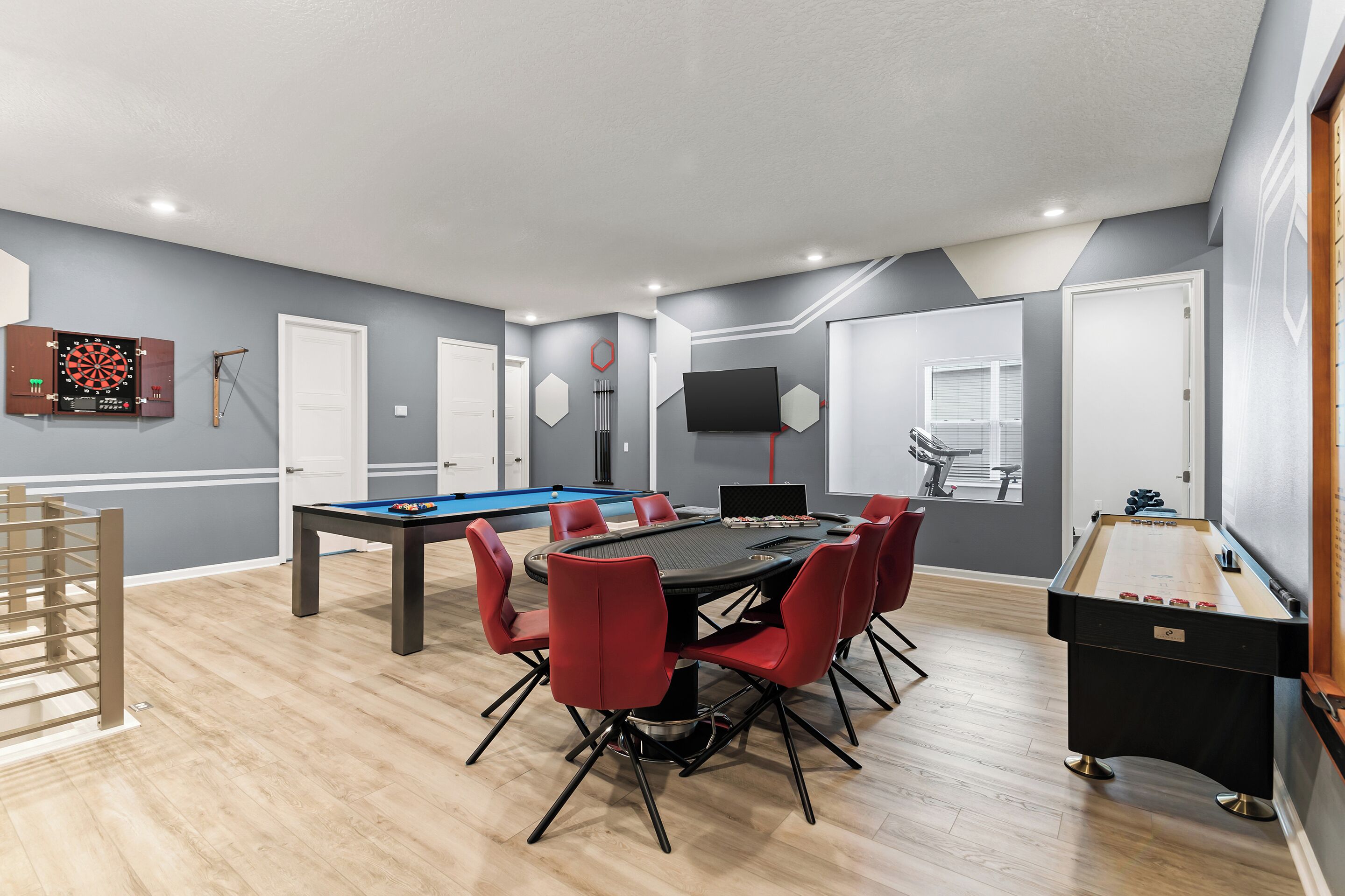A modern room with a pool table, foosball table, and dartboard.