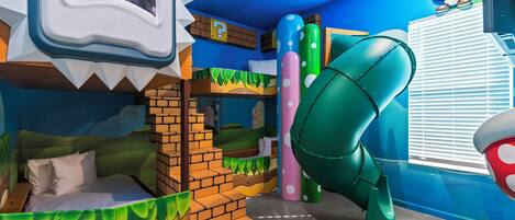 Un espace de jeux avec un toboggan, des structures d’escalade et un bac à sable.
